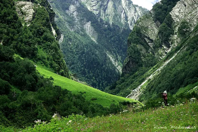 A trekker dwarfed by the valley's sheer green walls