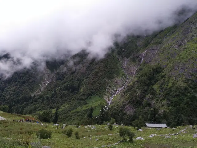 Cloud pouring down the slopes, with a forest hut below