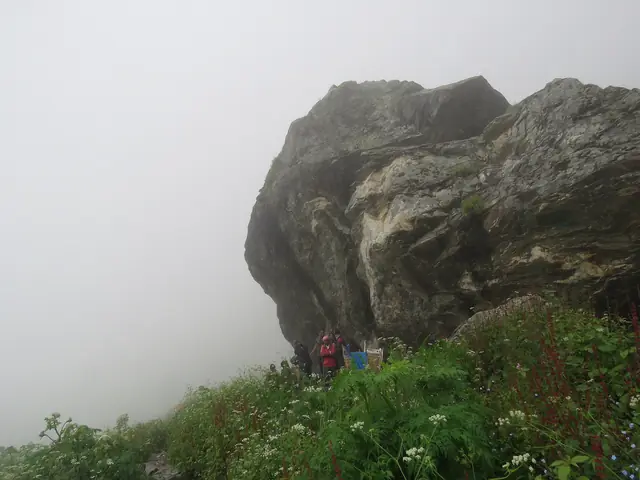Trekkers passing a giant boulder in the mist