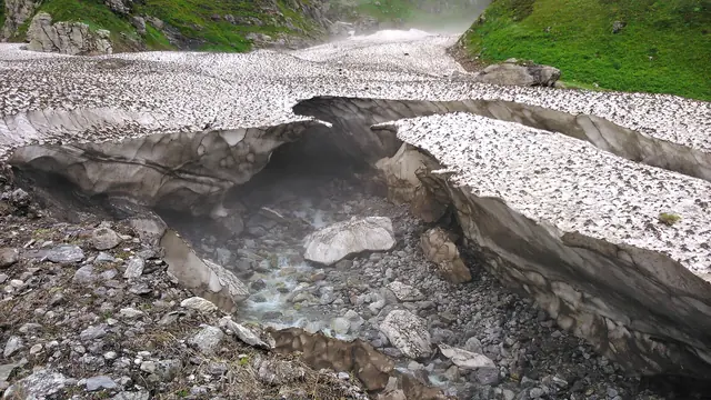 A stream tunnelling under glacier ice at the valley's edge